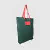 custom premium tote bag in green canvas with pink handles and badge