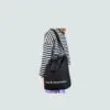 black A4 sling bag with removable shoulder carry strap being carried by person in stripy top