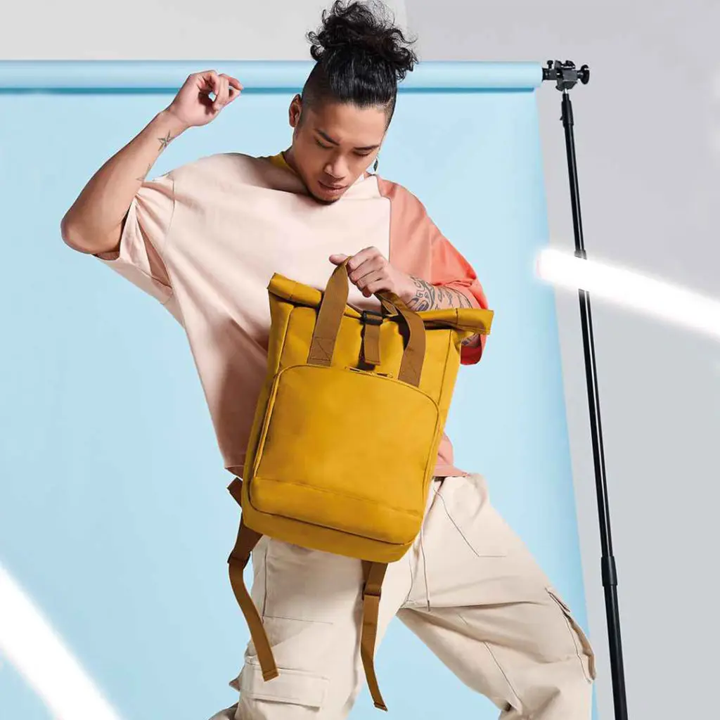 Man Holding Folding Top Mustard Backpack with Clip Closure
