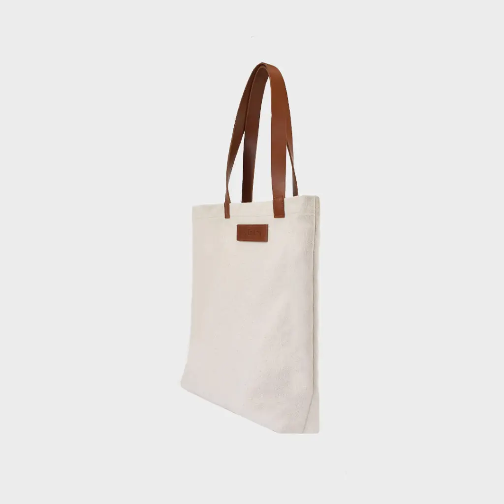 natural canvas tote bag with tan colour PU leather handles and embossed brand badge