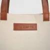 natural canvas tote bag with tan colour PU leather handles and embossed badge