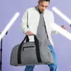 Man Holding Grey/Black handled Luggage Holdall