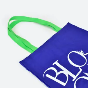 side view of blue tote bag with green handles