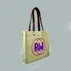 side view of a natural bag with leather handles and metal rivets. Print is orange and pink