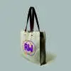 side view of a natural bag with leather handles and metal rivets. Print is orange and pink