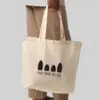 person wearing brown trousers holding a natural coloured bag with black print