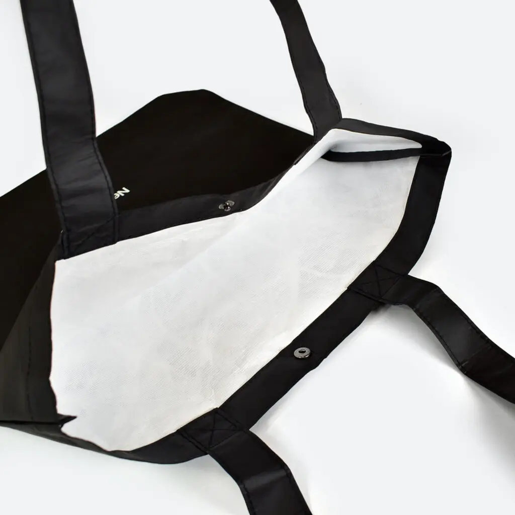 inside view of open tyvek bag that is black on outside and white on inside, taped seams and metal popper closure