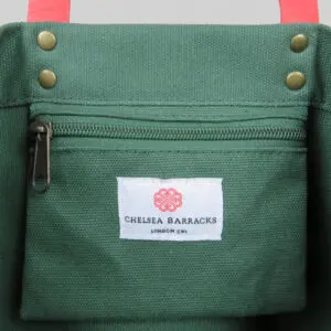 Green canvas tote bag with pink PU leather detail and woven label on inside pocket