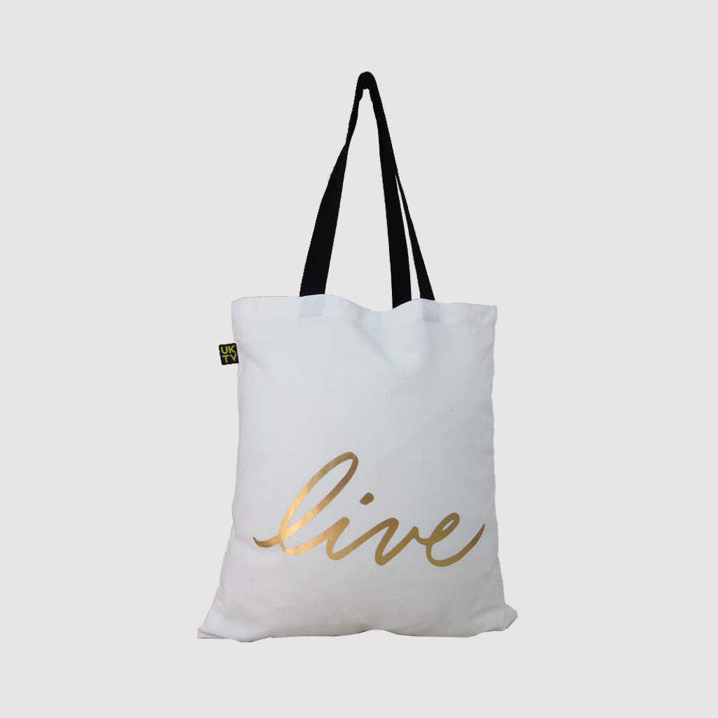 gold print on bag in white canvas with black handles and woven logo label