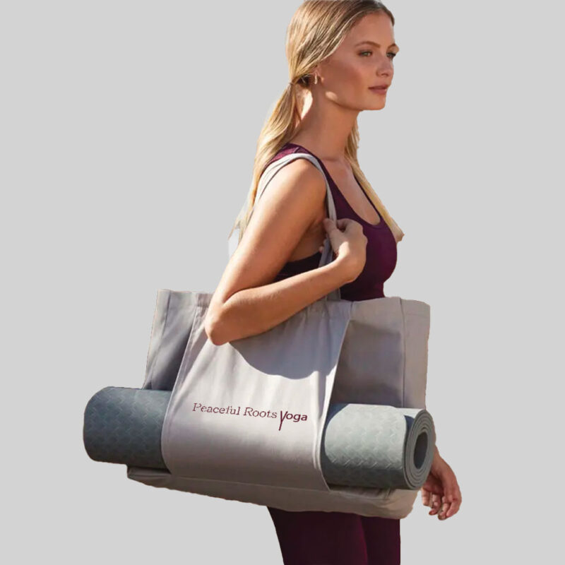 woman holding grey yoga bag with mat storage