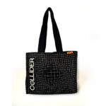 front view of black square tote bag with black handles hanging off hook. The bag is black with white check print and white text that spells COLLIDER with a orange rectangle woven label in the top seam