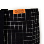 orange woven label is rectangle shape on the top seam of the black bag