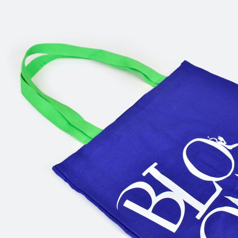 side view of blue tote bag with green handles