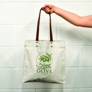 hand holding canvas tote with leather handles and logo print