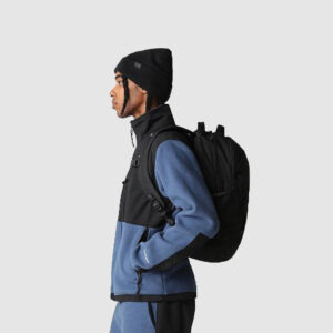 side view of person in black and blue jumper carrying a black branded bag on their bag