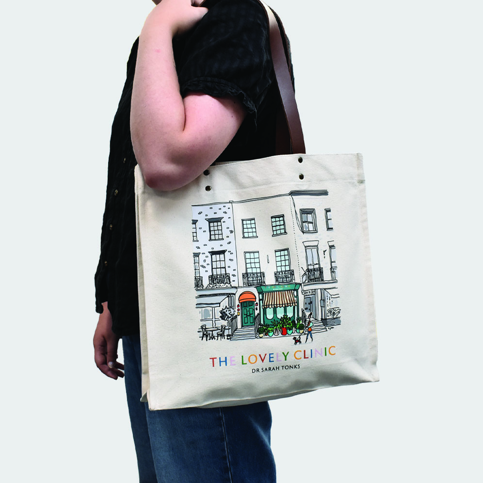 side view of tote bag with leather handles and bright print, carried by person in black top