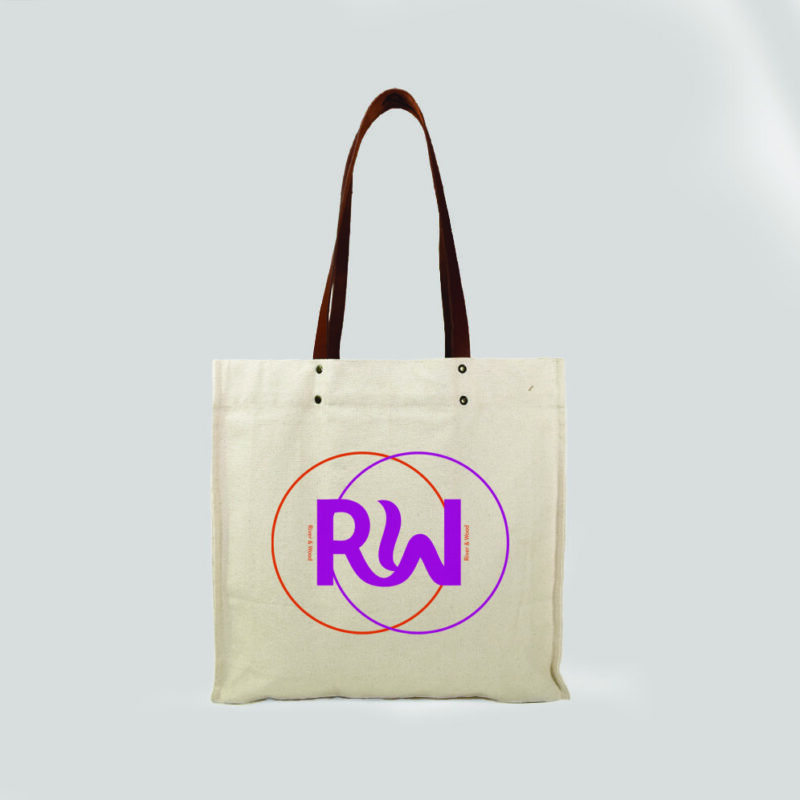 front view of a natural bag with leather handles and metal rivets. Print is orange and pink