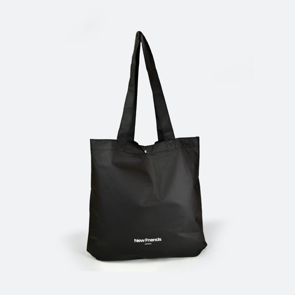 black tyvek tote bag with long handles and silver metal popper closure. White logo print.