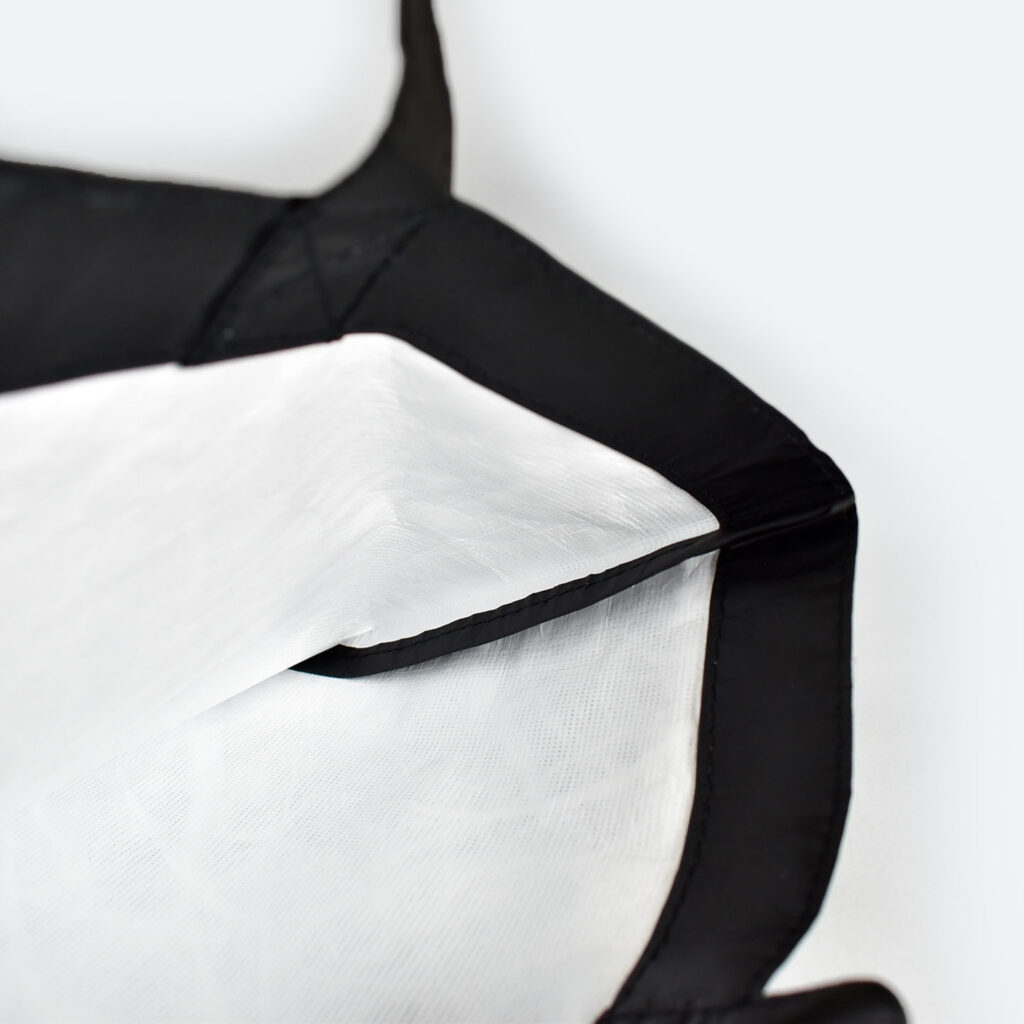 inside view of open tyvek bag that is black on outside and white on inside, taped seams and metal popper closure