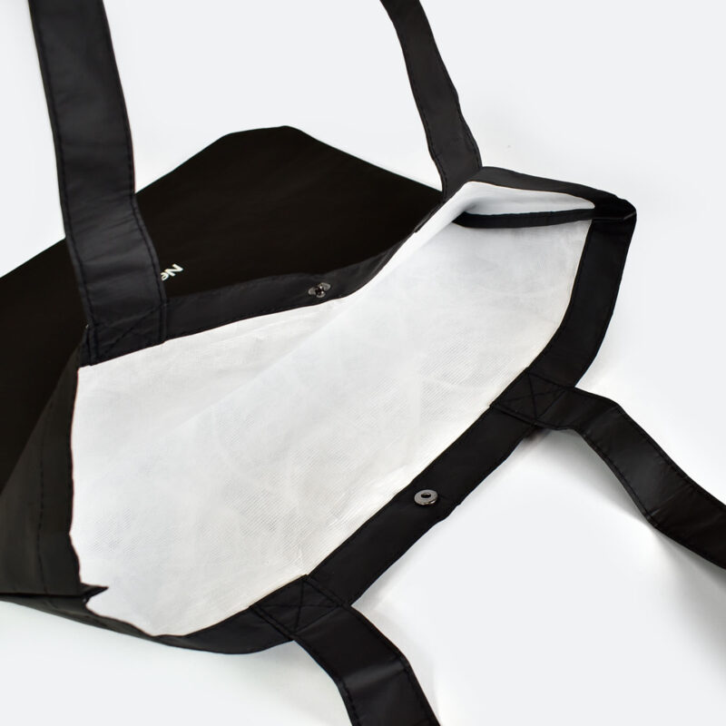 inside view of open tyvek bag that is black on outside and white on inside, taped seams and metal popper closure