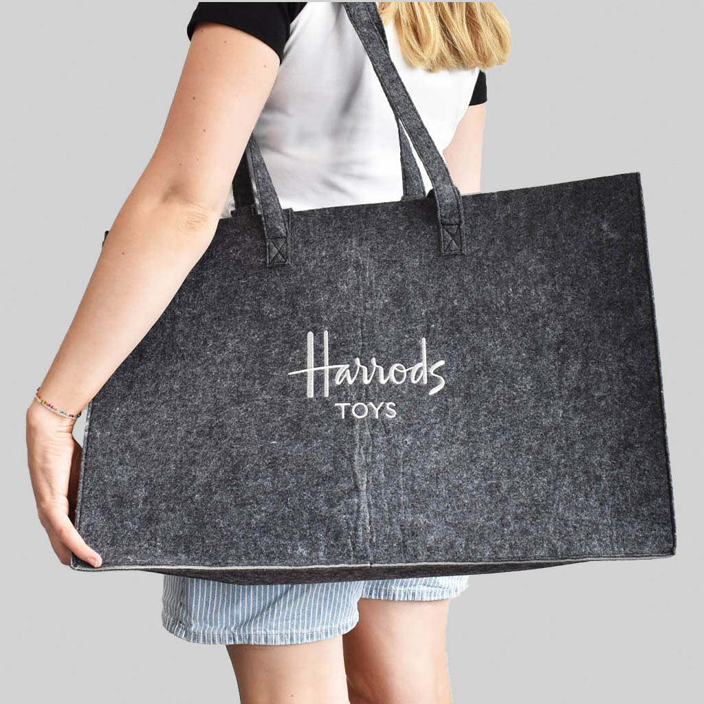 person carrying Harrods tote bag in grey felt