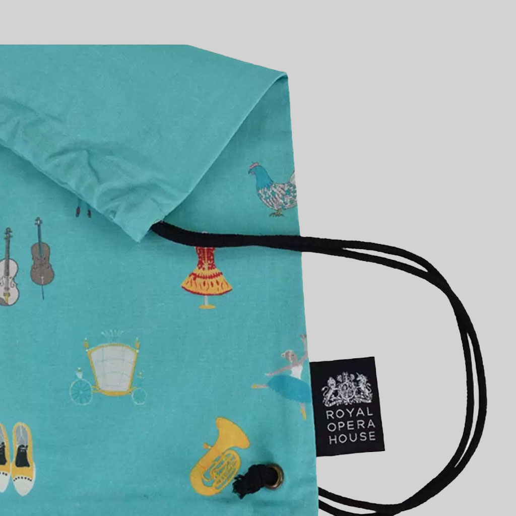 side view of cinch bag in light blue with black woven label with Royal Opera House logo how to work with a British vendor