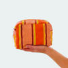 orange striped terry cloth wash bag held on the side by a hand