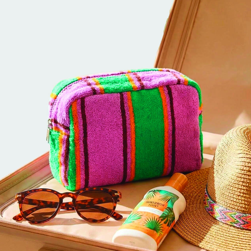 terry cloth wash bag on a table with sunglasses and sun cream next to it